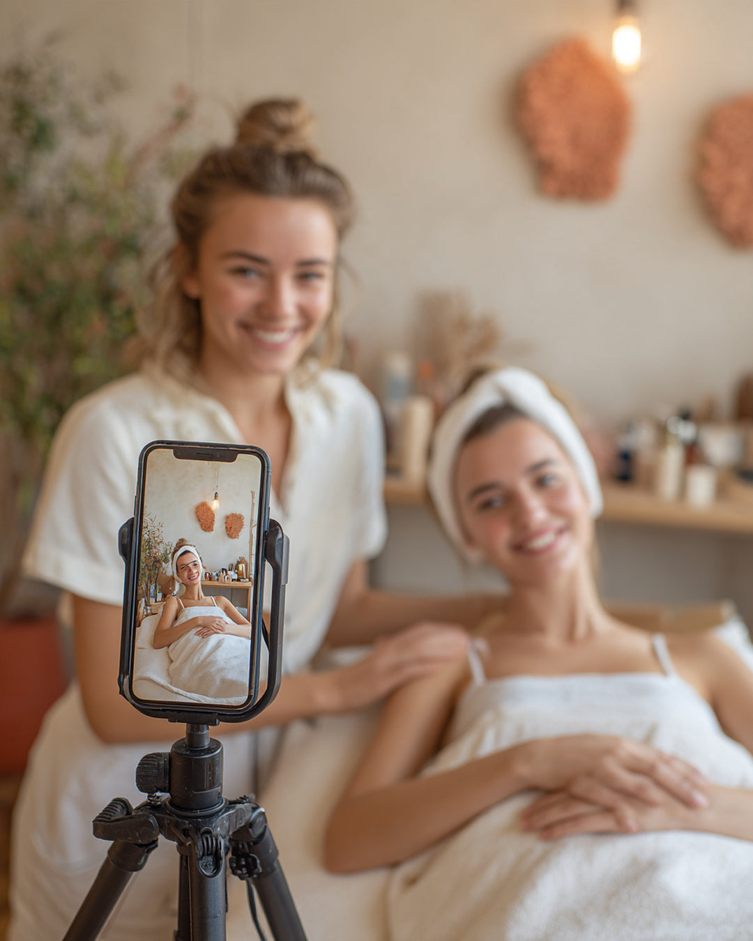 Estetista e cliente in cabina mentre registrano un video con il telefono